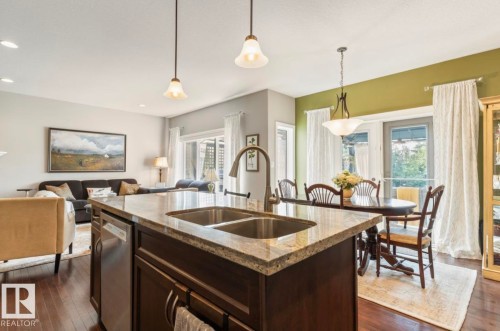 Kitchen island featuring a dual-basin stainless steel sink, granite countertop, and integrated stainless steel dishwasher - 22 Voleta Crest, Spruce Grove, AB - Indoor Photo Showing Kitchen With Double Sink With Upgraded Kitchen