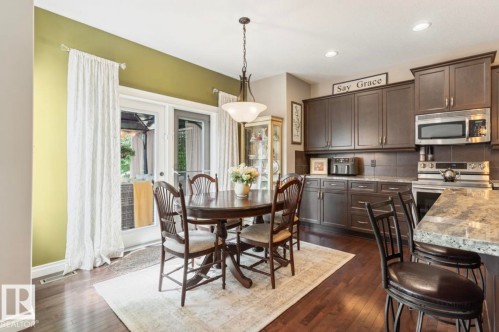 Kitchen and dining area featuring rich wood-finish flooring, dark cabinetry, and light-toned countertops - 22 Voleta Crest, Spruce Grove, AB - Indoor Photo Showing Dining Room