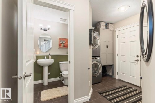 Dedicated laundry area featuring stacked front-load machines and built-in storage cabinetry - 22 Voleta Crest, Spruce Grove, AB - Indoor Photo Showing Laundry Room