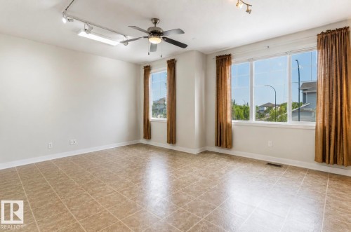 Spacious room featuring tile flooring, multiple windows providing ample natural light, a ceiling fan, and track lighting - 22 Voleta Crest, Spruce Grove, AB - Indoor Photo Showing Other Room