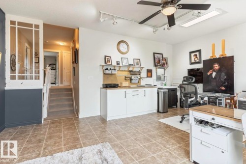 Spacious room featuring tile flooring, white cabinetry with black hardware, and a ceiling fan with integrated lighting - 22 Voleta Crest, Spruce Grove, AB - Indoor Photo Showing Kitchen