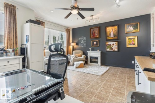 Versatile room featuring large windows, neutral tiled flooring, a decorative fireplace, a ceiling fan with integrated lighting, and track lighting - 22 Voleta Crest, Spruce Grove, AB - Indoor With Fireplace