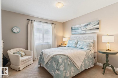 Carpeted bedroom featuring a window with privacy blinds and drapes, a ceiling-mounted light fixture, and neutral wall tones - 22 Voleta Crest, Spruce Grove, AB - Indoor Photo Showing Bedroom