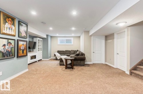 Spacious recreation room featuring recessed lighting, neutral carpeting, and a built-in media cabinet - 22 Voleta Crest, Spruce Grove, AB - Indoor Photo Showing Basement