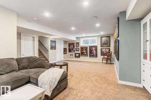 Spacious room featuring neutral carpeting, recessed lighting, a built-in white cabinet with glass doors, and a window providing natural light - 22 Voleta Crest, Spruce Grove, AB - Indoor