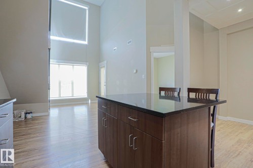 Kitchen island with dark wood-finish cabinetry and a dark countertop - #607 10518 113 St Nw Nw, Edmonton, AB - Indoor