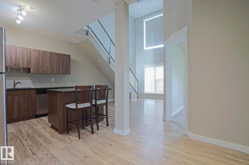 Kitchen featuring wood-finish cabinetry, stainless steel dishwasher, and a center island with counter seating - #607 10518 113 St Nw Nw, Edmonton, AB - Indoor