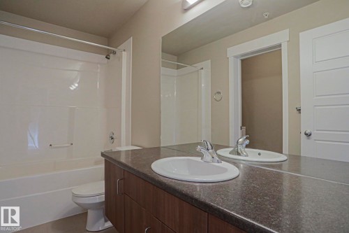 Double vanity with undermount sinks, wood-finish cabinetry, and a full-width mirror - #607 10518 113 St Nw Nw, Edmonton, AB - Indoor Photo Showing Bathroom