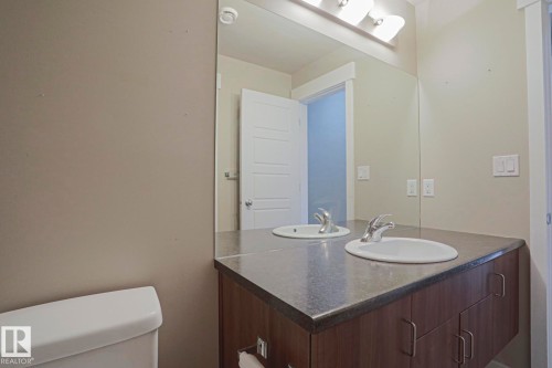 Dual vanity with integrated sinks, wood-finish cabinetry, and a full-width mirror - #607 10518 113 St Nw Nw, Edmonton, AB - Indoor Photo Showing Bathroom