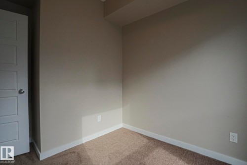 Neutral-toned walls with contrasting white trim, plush carpeting, and a paneled interior door - #607 10518 113 St Nw Nw, Edmonton, AB - Indoor Photo Showing Other Room