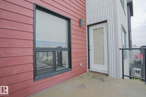 Exterior balcony with a frosted-glass door, black-framed window, horizontal siding, and glass panel railing - #607 10518 113 St Nw Nw, Edmonton, AB - Outdoor With Balcony With Exterior