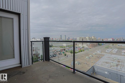 Balcony featuring a glass panel railing, metal exterior siding, and an opaque glass-paneled door - #607 10518 113 St Nw Nw, Edmonton, AB - Outdoor With Balcony With View