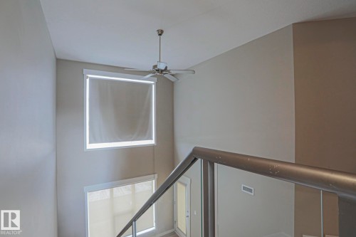Interior staircase with metal railing, high ceilings, and multiple windows with roller shades - #607 10518 113 St Nw Nw, Edmonton, AB - Indoor Photo Showing Other Room