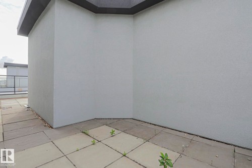 Tiled outdoor patio space with stucco wall exterior and dark trim - #607 10518 113 St Nw Nw, Edmonton, AB -  With Exterior