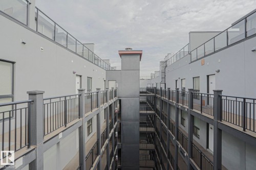 Multi-level building exterior featuring smooth gray siding, black metal railings, and glass balcony enclosures - #607 10518 113 St Nw Nw, Edmonton, AB - Indoor Photo Showing Other Room