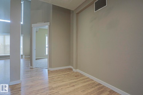 Wood-finish flooring, neutral wall tones, white trim, and multiple large windows - #607 10518 113 St Nw Nw, Edmonton, AB - Indoor Photo Showing Other Room