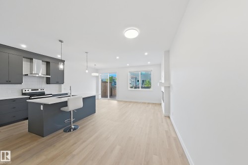Open-concept living space featuring light wood-finish flooring throughout - 7791 Eifert Crescent Nw, Edmonton, AB - Indoor Photo Showing Kitchen