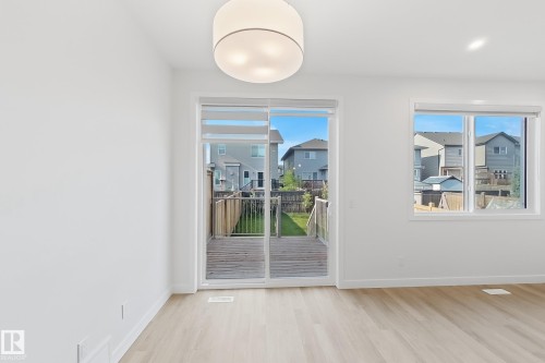 Bright room featuring wood-finish flooring, white walls, and a contemporary flush-mount ceiling light - 7791 Eifert Crescent Nw, Edmonton, AB - Indoor Photo Showing Other Room