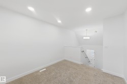 Carpeted floor area featuring recessed lighting, a vaulted ceiling, and a modern drum pendant light fixture illuminating the stairwell - 