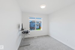 Bright room featuring a large window, neutral gray carpeting, white baseboards, and a flush-mount ceiling light - 