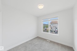 Room featuring a large window with white trim, neutral carpet flooring, a flush-mount ceiling light fixture, and white painted walls - 