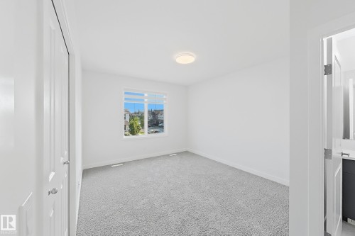 Spacious room featuring light gray carpeting, a large window, and white walls - 7791 Eifert Crescent Nw, Edmonton, AB - Indoor Photo Showing Other Room