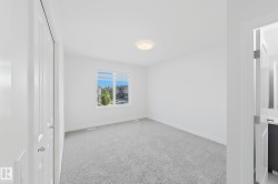 Spacious room featuring light gray carpeting, a large window, and white walls - 