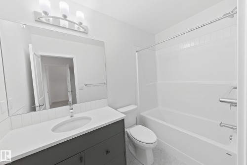 Modern bathroom featuring a single vanity with a white countertop, undermount sink, and dark gray cabinetry - 7791 Eifert Crescent Nw, Edmonton, AB - Indoor Photo Showing Bathroom
