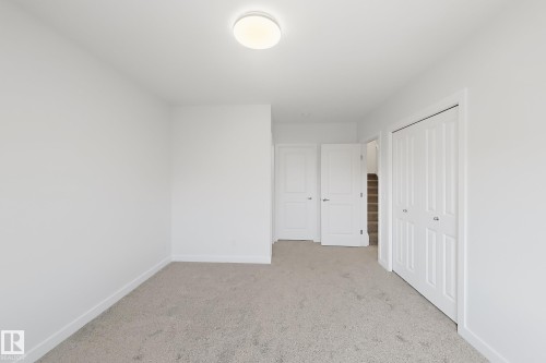 Interior room featuring light gray carpet flooring, white painted walls, and a flush-mount ceiling light fixture - 7791 Eifert Crescent Nw, Edmonton, AB - Indoor Photo Showing Other Room