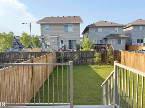 Rear yard featuring a manicured lawn, new wood fencing, and a light-colored railing system - 7791 Eifert Crescent Nw, Edmonton, AB - Outdoor With Exterior