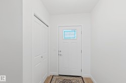 Entryway featuring a paneled door with glass insert, light wood-finish flooring, and a white bi-fold closet door - 
