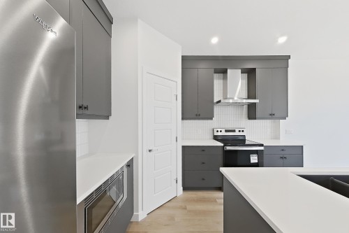 Modern kitchen featuring sleek gray cabinetry, stainless steel appliances, white countertops, and a white subway tile backsplash - 7791 Eifert Crescent Nw, Edmonton, AB - Indoor Photo Showing Kitchen