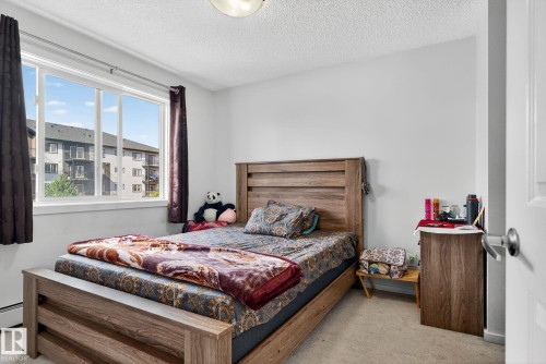 Neutral wall paint, carpet flooring, and a wood-finish bed frame - 3353 16A Avenue Nw, Edmonton, AB - Indoor Photo Showing Bedroom