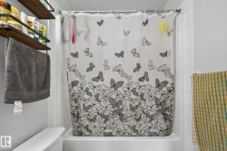 Fiberglass tub with a white shower surround, accompanied by wall-mounted shelving and a towel bar - 