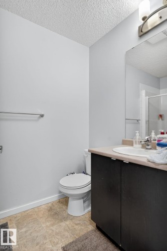 Vanity with dark wood-finish cabinetry, integrated sink, and light-toned countertop - 3353 16A Avenue Nw, Edmonton, AB - Indoor Photo Showing Bathroom