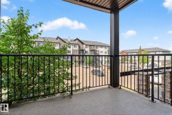 Private balcony with concrete flooring, black metal railings, and an overhead trellis - 