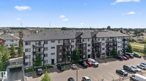 Modern multi-level building with individual private balconies, a large surface parking lot, and an integrated underground parking garage - 3353 16A Avenue Nw, Edmonton, AB - Outdoor