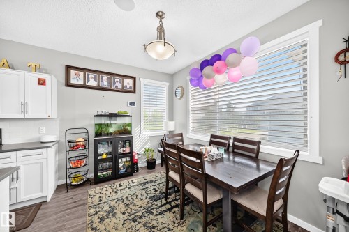White shaker-style cabinetry with matte gray countertops, wood-finish flooring, and a large window with white trim - 1929 24 Street Nw, Edmonton, AB - Indoor Photo Showing Dining Room
