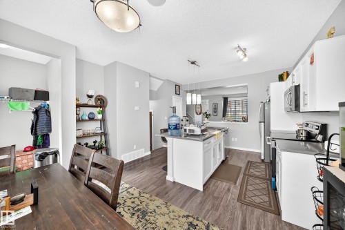 Kitchen featuring white cabinetry, stainless steel appliances, an island with pendant lighting, and wood-finish flooring - 1929 24 Street Nw, Edmonton, AB - Indoor