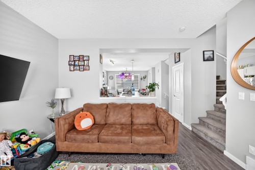 Open-concept living space with wood-finish flooring, a neutral color palette, and a carpeted staircase - 1929 24 Street Nw, Edmonton, AB - Indoor Photo Showing Living Room