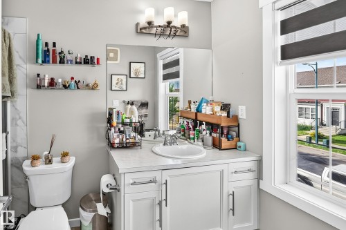 Bright bathroom featuring a white vanity with dual-sink configuration, quartz countertop, and chrome hardware - 1929 24 Street Nw, Edmonton, AB - Indoor Photo Showing Bathroom