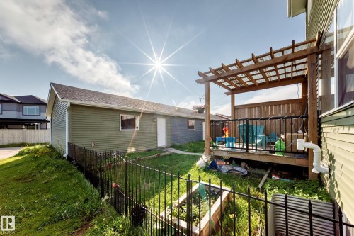 Rear deck featuring a wood pergola with a clear panel roof, black metal railings, and wood privacy screening - 1929 24 Street Nw, Edmonton, AB - Outdoor With Deck Patio Veranda With Exterior