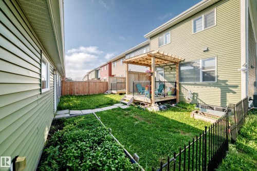 Rear exterior featuring a wooden deck with a pergola, a wooden privacy fence, and a grass lawn with stone pavers - 1929 24 Street Nw, Edmonton, AB - Outdoor With Deck Patio Veranda With Exterior