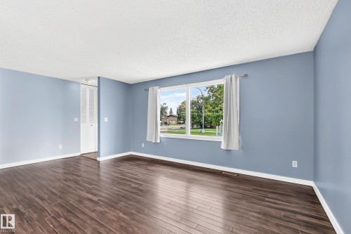 Wood-finish flooring, a large window with white trim, and a white bi-fold door - 16808 100 Street Nw, Edmonton, AB - Indoor Photo Showing Other Room