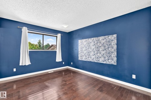 Wood-finish flooring with white trim - 16808 100 Street Nw, Edmonton, AB - Indoor Photo Showing Other Room