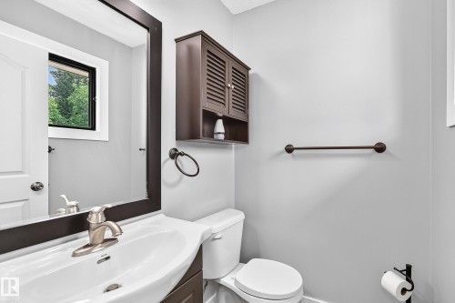 Integrated vanity with an undermount sink, brushed nickel faucet, wall-mounted mirror, and dark wood-finish cabinet - 16808 100 Street Nw, Edmonton, AB - Indoor Photo Showing Bathroom
