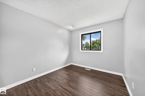 Wood-finish flooring, light gray wall paint, and a window with black trim - 16808 100 Street Nw, Edmonton, AB - Indoor Photo Showing Other Room