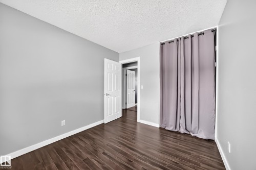 Wood-finish flooring with a satin finish, neutral wall paint, and white trim - 16808 100 Street Nw, Edmonton, AB - Indoor Photo Showing Other Room