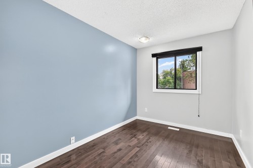 Hardwood-style flooring, white trim, and a window with a roller shade - 16808 100 Street Nw, Edmonton, AB - Indoor Photo Showing Other Room