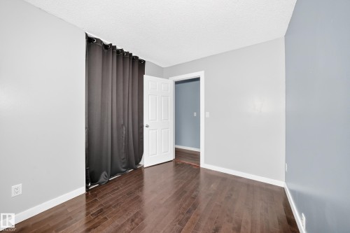 Rich wood-finish flooring with white trim - 16808 100 Street Nw, Edmonton, AB - Indoor Photo Showing Other Room